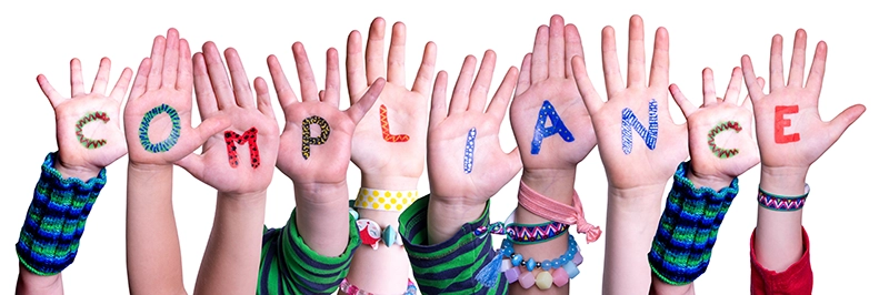 The word compliance spelled out on children's hands